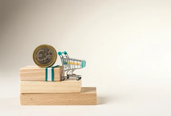 Imagen explicativa sobre qué es la deflación. Moneda de euro y carrito de la compra sobre escalera de madera